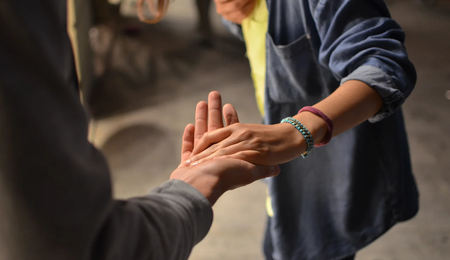 Two people touching hands. One person has two bracelets.